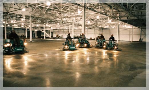 Multiple concrete smoothing/flattening machines in a warehouse, services done by B&B Concrete Placement, Inc